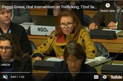 [ai] A woman wearing glasses and a colorful coat speaks at a conference table, with participants in the background. A sign reading 'NGOs' is visible behind her, indicating the organizational context of the event.